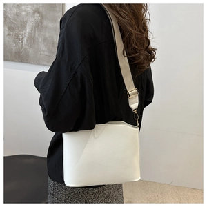 Detail of white leather shoulder bag with wide textile strap and gold metal hardware