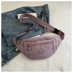 Détail d'un sac banane de sport en nylon lavande avec poches zippées sur veste en jean