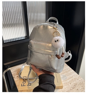 Nahaufnahme silberner geometrischer PU-Rucksack mit niedlichem Monster-Plüschanhänger
