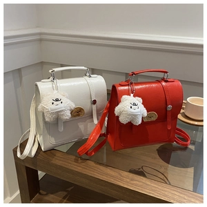 Close-up of glossy mini backpacks in white and red with cute bear charms and textures