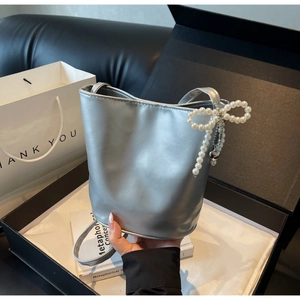 Detail view of silver bucket bag with pearl bow and heart pendant in a gift box