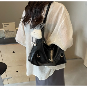 Detail of black leather tote bag with silver butterfly charms and white plush pendant