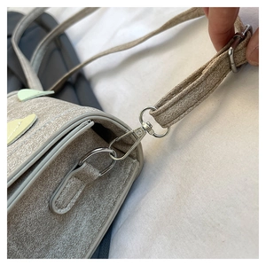 Detail of silver swivel clasp and D-ring on textured light gray crossbody bag