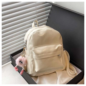 Detail of cream PU leather mini backpack in a gift box with a pink plush charm