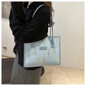 Model wearing a light blue pleated tote bag with wavy embroidery and metal logo
