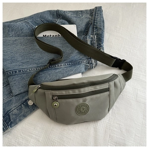 Détail de la banane en nylon vert sauge avec compartiments zippés et sangle tissée