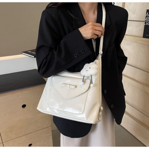 Detail of off-white patent leather tote with bow and plush cloud charm accessory