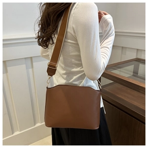 Brown vintage faux leather crossbody bag worn by a model in a minimalist indoor setting