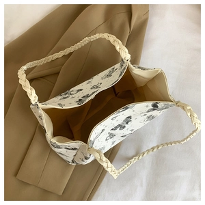 Detail of printed tote bag featuring braided rope handles and yellow interior lining