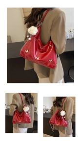 Macro detail of red glossy leather tote with silver butterfly charms and cloud pendant