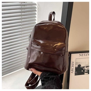 Macro detail of deep brown high-gloss leather backpack with polished texture