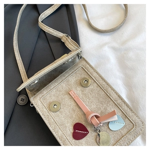 Detail view of the heart decorations and shiny fabric texture on the small crossbody bag