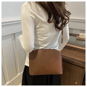 Minimalist chocolate leather shoulder bag with gold hardware detail in lifestyle setting