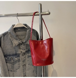 Detail of red leather bucket bag with white fashion text hanging on a rack