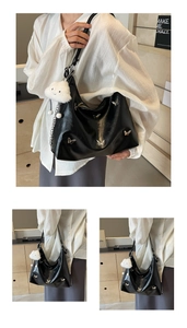 Detail of black leather Hobo bag with silver butterfly studs and a white plush charm