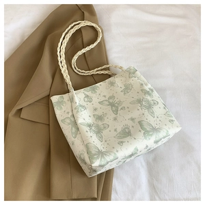 Detailed view of white tote bag featuring light green butterfly patterns and woven rope handles