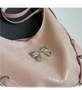 Dettaglio della borsa in pelle rosa perlato con elegante fiocco in metallo argento