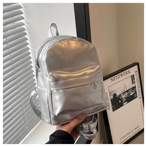 Detail of a shiny silver faux leather backpack with metallic finish and zipper pockets