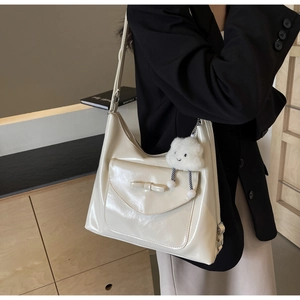 Detail of cream white tote bag with bow accent and cloud plush charm on a shoulder strap