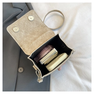 Detail of glittery mini crossbody bag interior with dual magnetic closure and pink contents