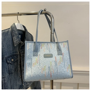 Close-up of light blue tote bag with embossed diamond texture and colorful zigzag stitching
