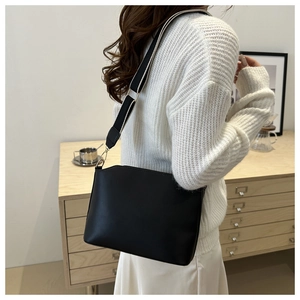 Detail of black trapezoid crossbody bag with adjustable wide contrast fabric strap