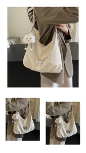 Detail of cream hobo bag featuring butterfly metal chain and fluffy cloud charm