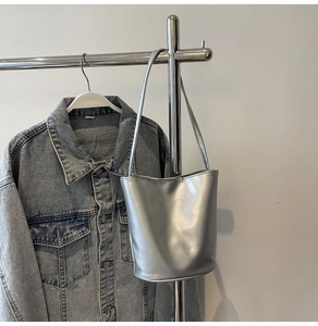 Detail of silver metallic bucket bag with pearl bow and slim shoulder strap hanging on rack