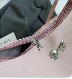 Dettaglio della borsa a spalla rosa con fiocco metallico e cerniera rettangolare