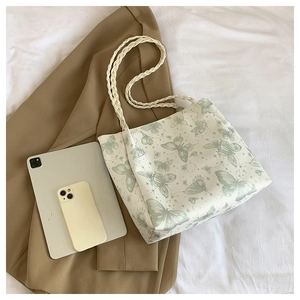 Detail of canvas tote bag with butterfly print and woven rope straps on a beige background