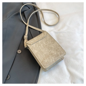 Close-up of beige crossbody phone bag with distressed leather texture and metal buckle