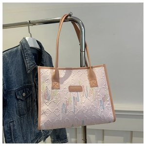 Detail of pink tote bag with embossed letters and colorful wavy embroidery texture