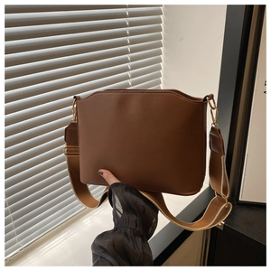 Detail of vintage brown shoulder bag showing wave edge design and wide textile strap