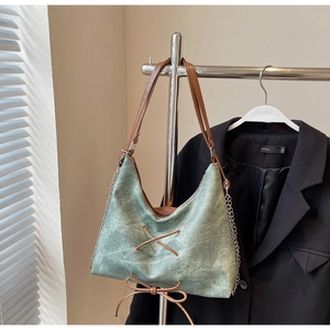 Dettaglio della borsa tote bohémien in tela verde con lacci in pelle marrone e catena