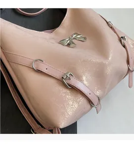 Dettaglio della borsa tote rosa metallizzata con fiocco argento e cinturini a fibbia