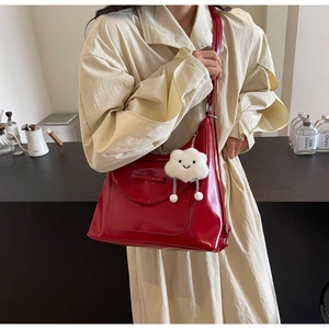 Detail of red glossy tote bag featuring a bow decoration and white cloud plush charm