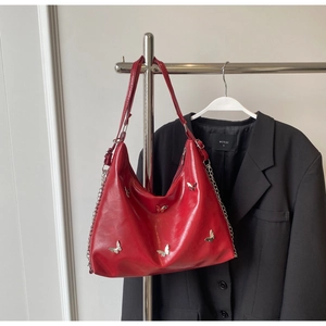 Detail of red leather tote bag with silver butterfly charms and chain strap detail