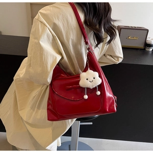 Detail of red faux leather shoulder bag with bow decoration and white plush cloud pendant