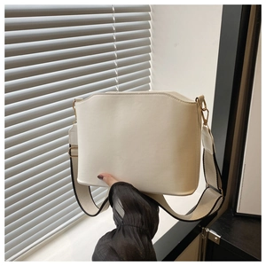 Detail of cream leather shoulder bag with wavy top edge and stylish striped strap