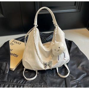 Close-up of white soft leather tote with silver butterfly chain and plush cloud charm