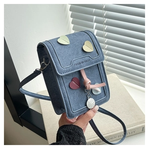 Close-up of blue crossbody phone bag with colorful heart patches and stylish pendants