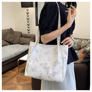 Detailed view of white tote bag featuring gray butterfly prints and woven handles