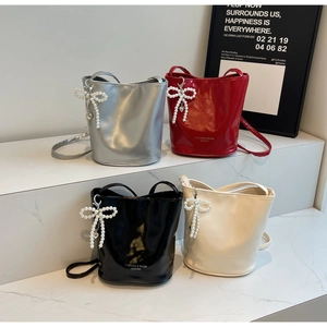 Detail of four colorful bucket bags with pearl bow charms and elegant fashion lettering