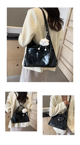 Close-up of black glossy patent tote bag with bow detail and plush cloud charm