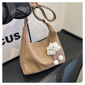 Detail of brown matte leather half-moon tote bag with a cute white cloud plush charm