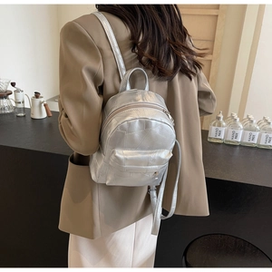 Rucksack aus silbernem Metallic-PU-Leder mit Steppnähten auf dem Rücken des Models