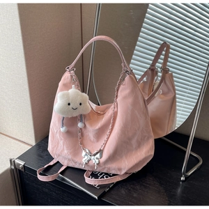 Close-up of pink pleated tote bag with metal butterfly and plush cloud charms