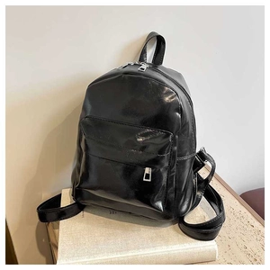 Detail of black glossy PU leather backpack with silver zippers and front pocket