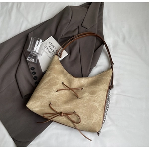 Dettaglio della borsa tote in tela kaki con lacci in pelle marrone e catena metallica