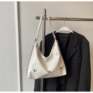 Detail of white half-moon shoulder bag featuring five silver metal butterfly buckles and chain